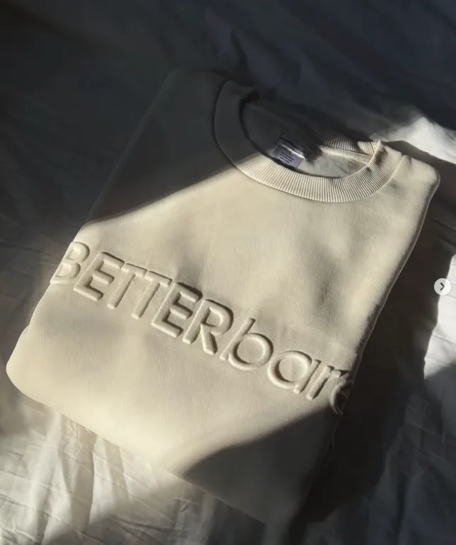 Cream bareMinerals sweatshirt embossed with the words Better bare, lit by sunlight