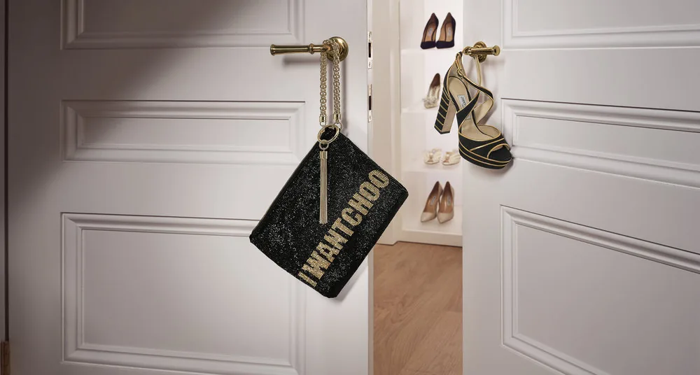 Jimmy Choo FW18 still life: an I Want Choo clutch hangs from a door handle beside heels, by Maxime Poiblanc