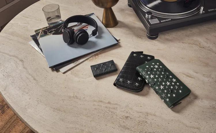 Jimmy Choo FW18 still life: star-studded wallets and headphones on a travertine table, by Maxime Poiblanc