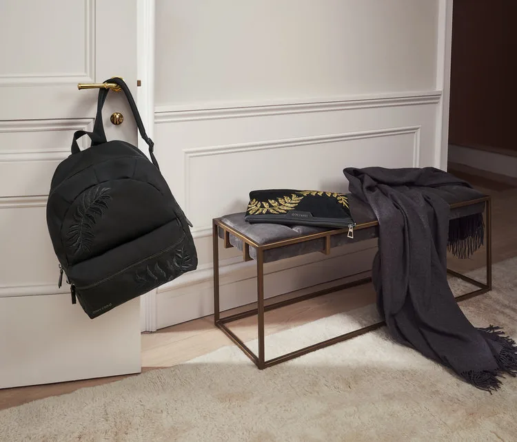 Jimmy Choo FW18 still life: a black backpack on a hook beside a bench with a scarf, by Maxime Poiblanc