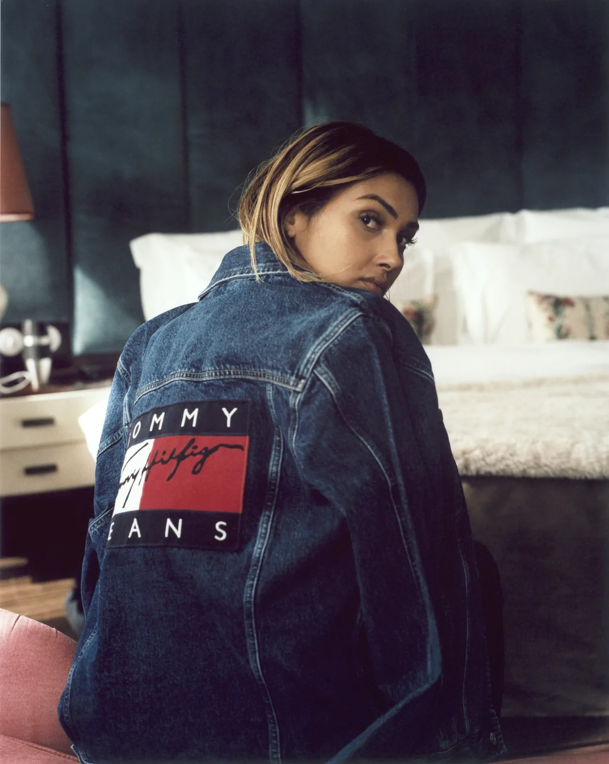 Influencer in a Tommy Jeans denim jacket looking back over her shoulder in a bedroom