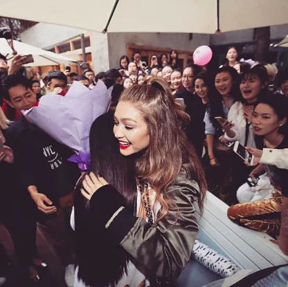 Gigi Hadid hugs a fan holding a bouquet in a crowd, Tommy x Gigi tour, Shanghai