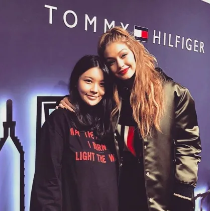 Gigi Hadid with a fan in front of a Tommy Hilfiger backdrop, Tommy x Gigi tour