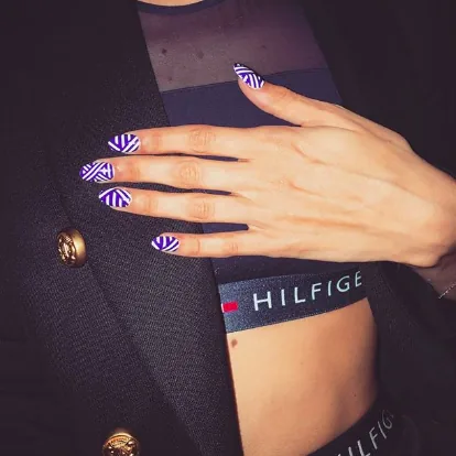 Hand with striped nail art resting on a Hilfiger logo waistband, tour social post