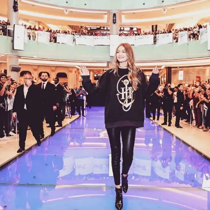 Gigi Hadid walks a runway through a mall atrium with crowds on every balcony, Tommy x Gigi tour, Dubai