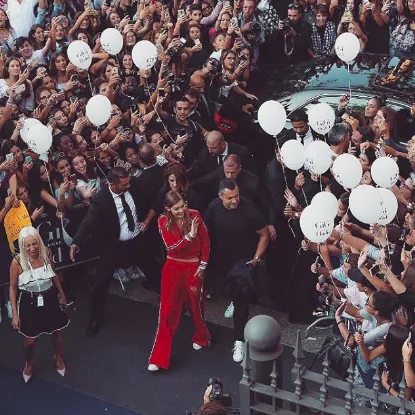 Gigi Hadid in red waves to a crowd holding white balloons, Tommy x Gigi tour, Milan