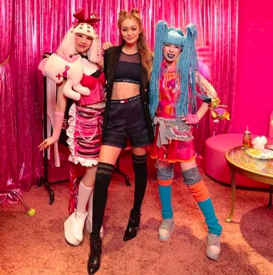 Gigi Hadid between two Harajuku-styled fans in front of a pink curtain, Tommy x Gigi tour, Tokyo