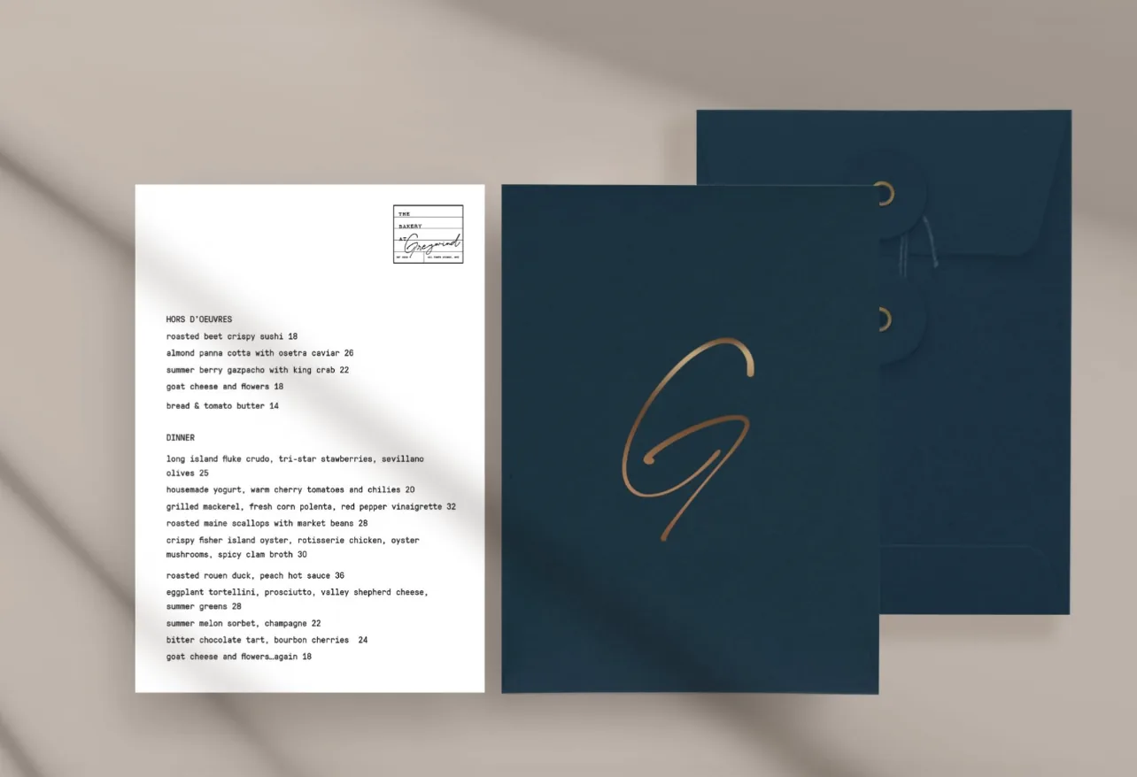 Greywind menu card beside navy envelopes stamped with a gold G monogram