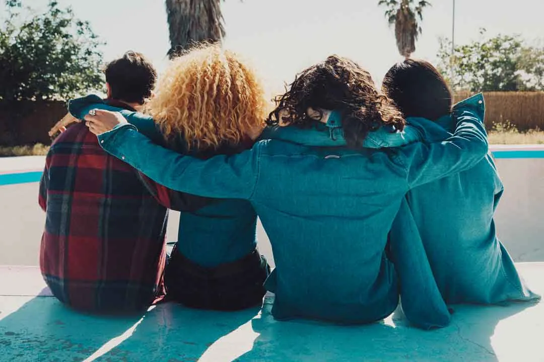 Three friends seen from behind with arms around each other in an empty pool, shot by Bryant Eslava