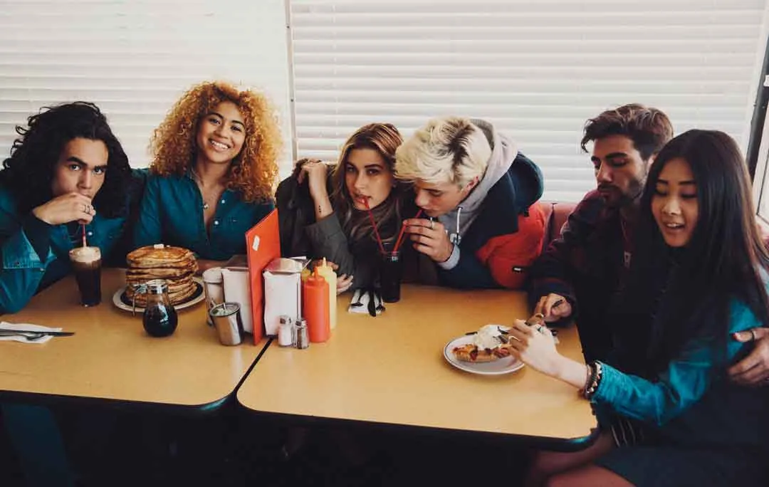 Friends crowded around a diner table with pancakes and milkshakes, shot by Bryant Eslava