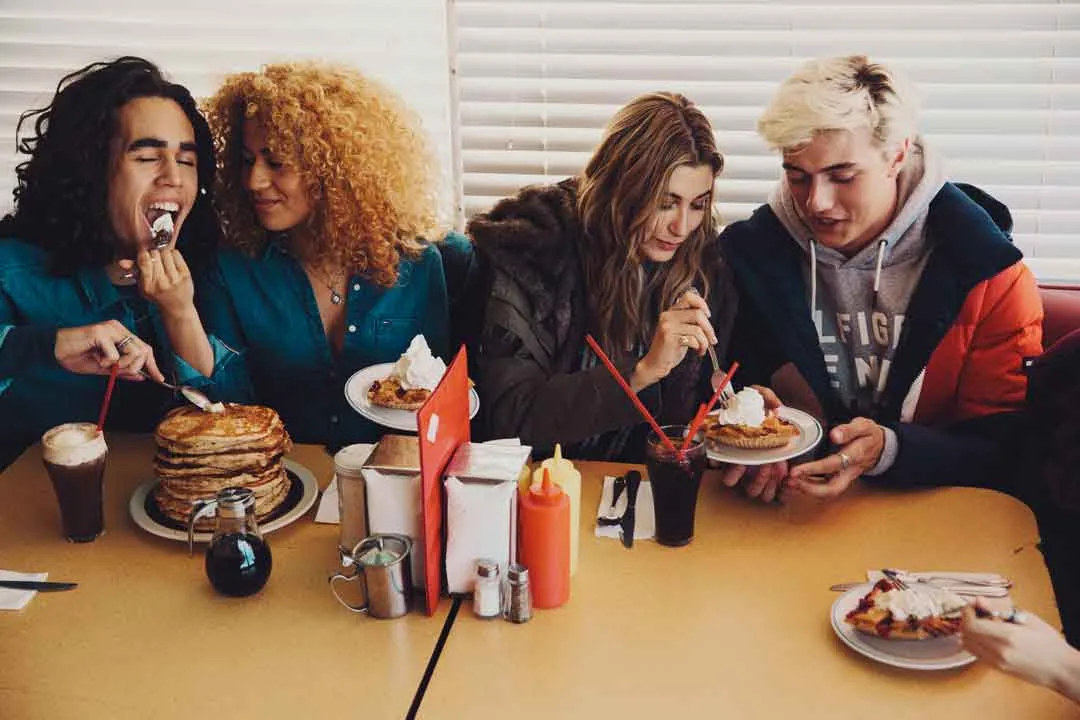 Friends sharing pancakes and sundaes at a diner table, shot by Bryant Eslava