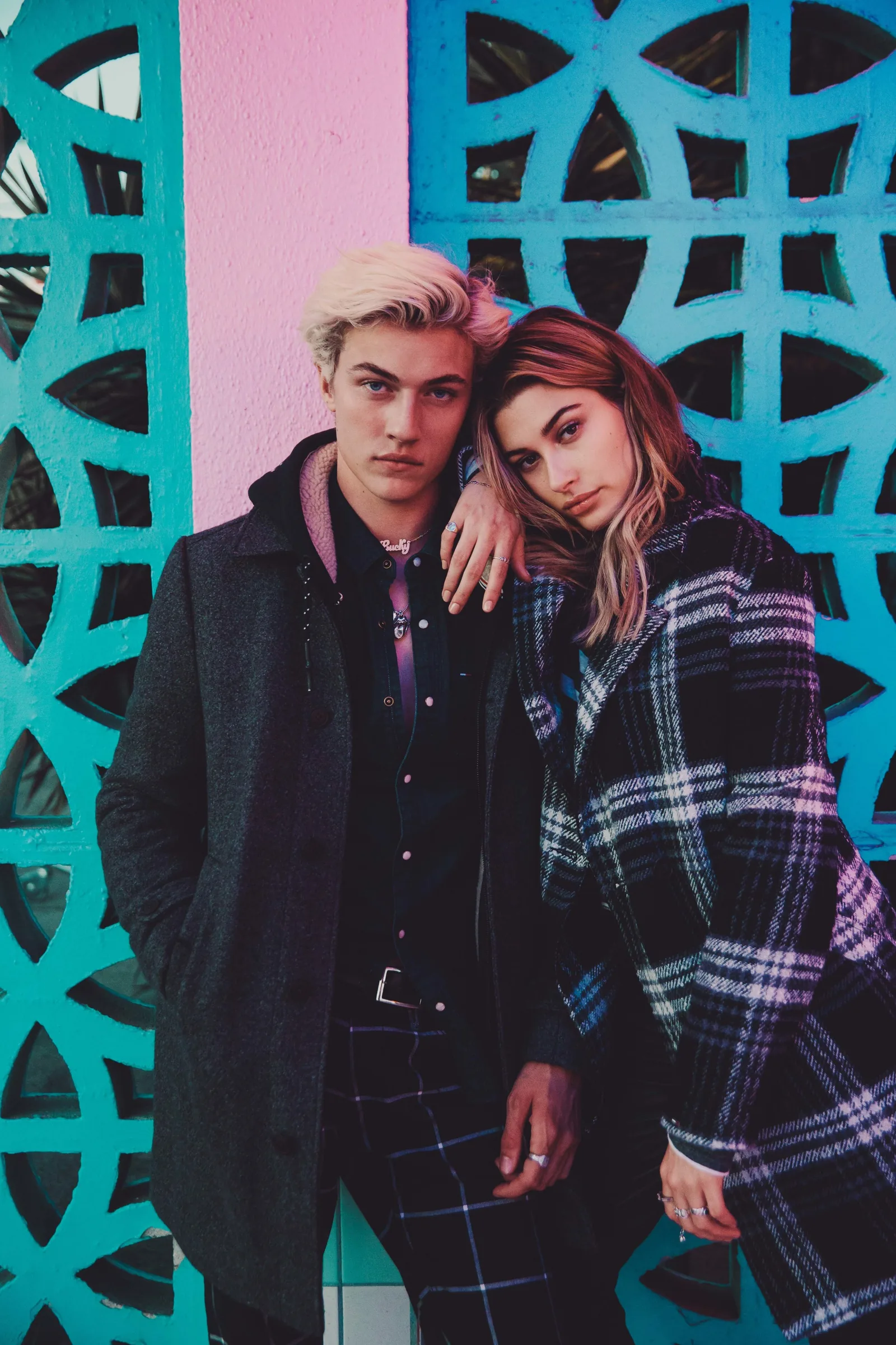 Lucky Blue Smith and Hailey Baldwin in coats against a turquoise breeze-block wall, shot by Bryant Eslava
