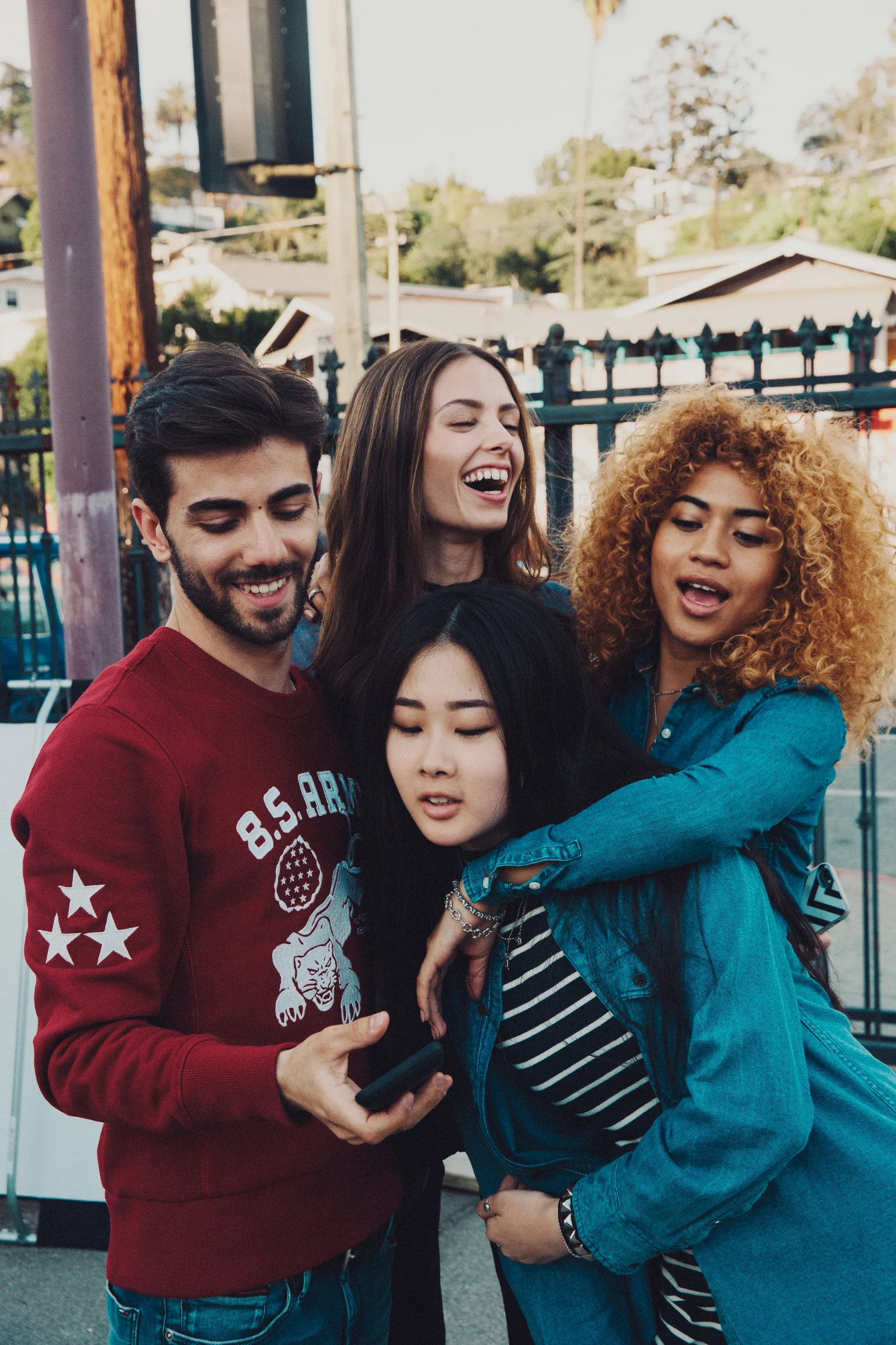 Four friends in denim in a group hug on an LA street, shot by Bryant Eslava
