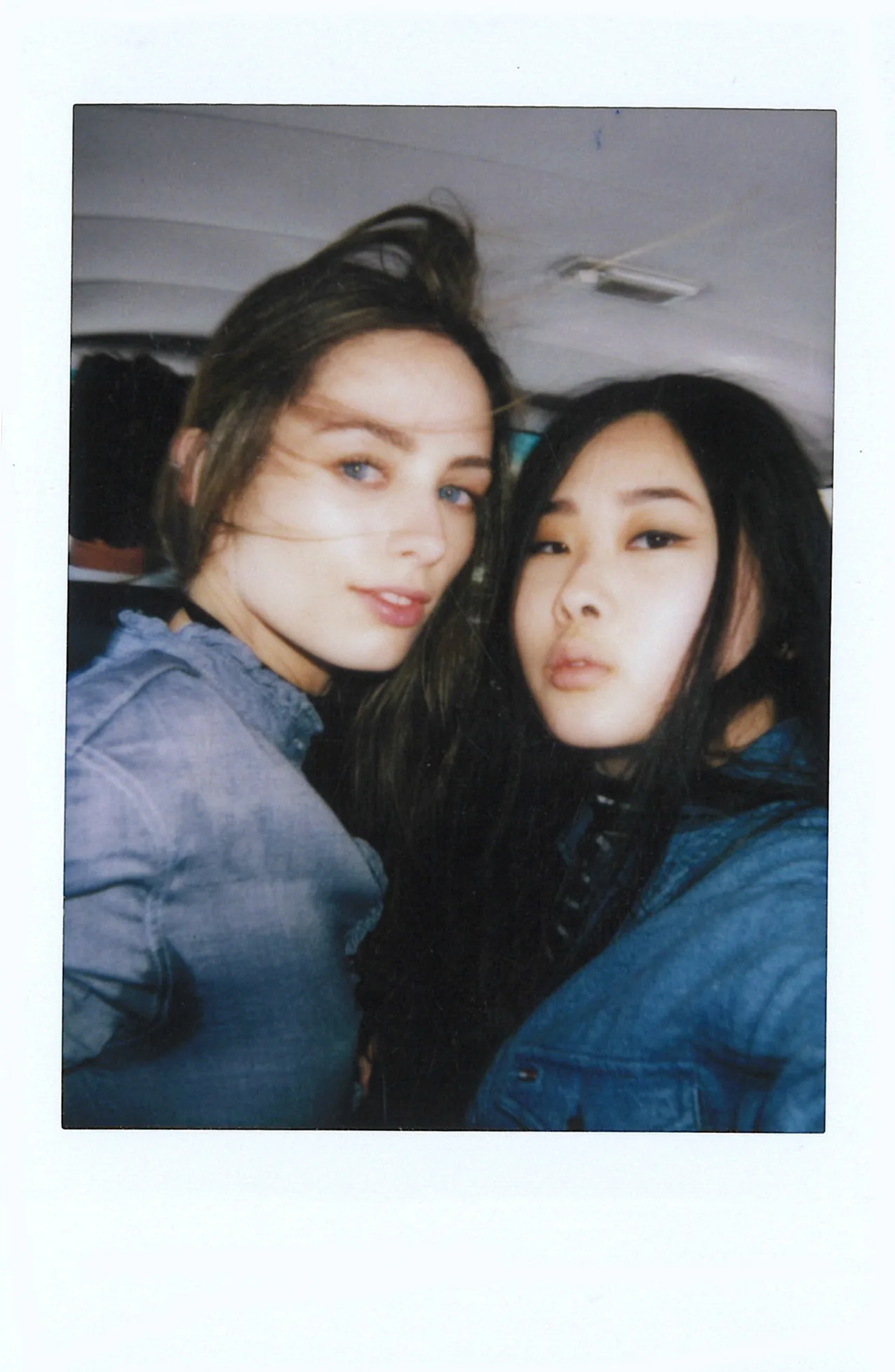 Polaroid of two women in denim jackets in the back of a car