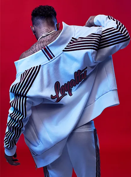 Tommy Icons campaign still: a man seen from behind in a white Loyalty varsity jacket against a red backdrop