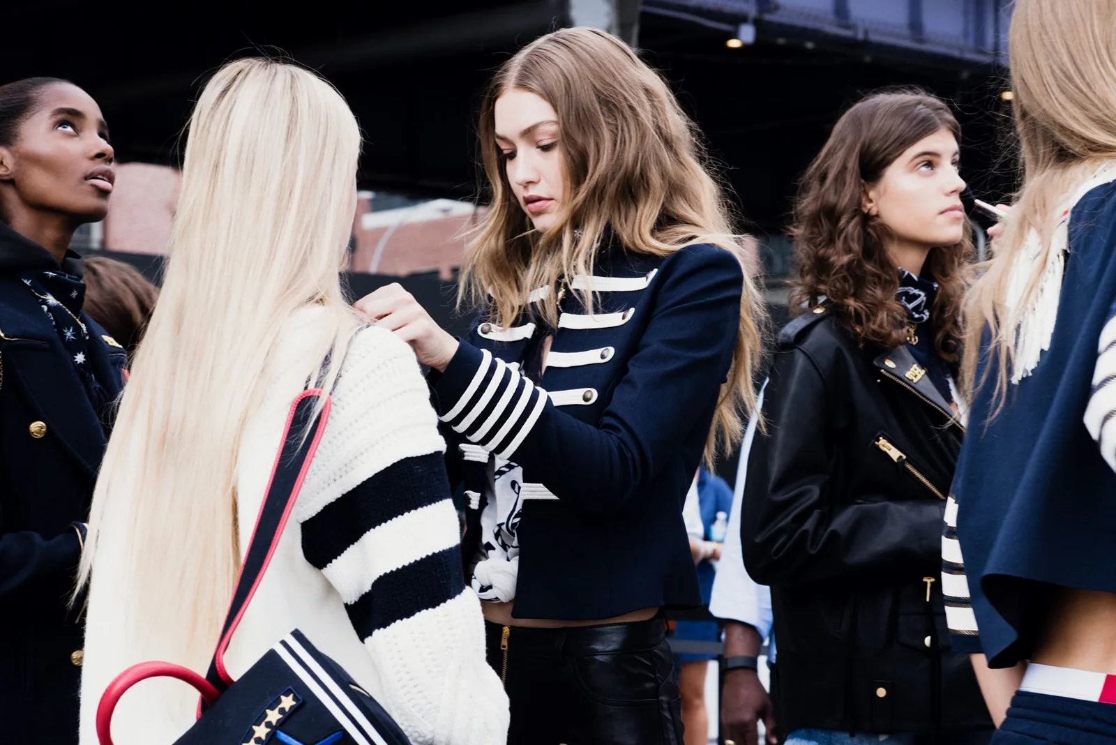 TommyNow backstage: Gigi Hadid in a navy military jacket having her look adjusted