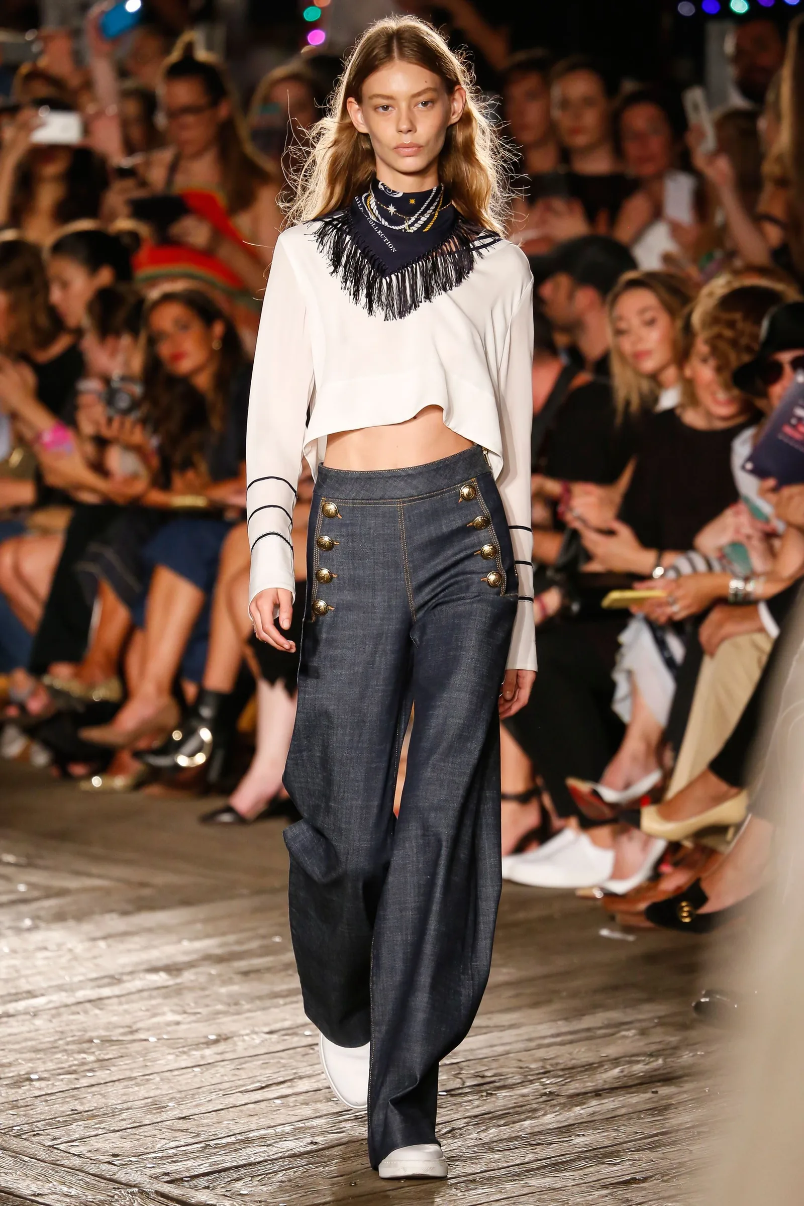 TommyNow runway look: a model in a white cropped top, bandana and navy sailor trousers